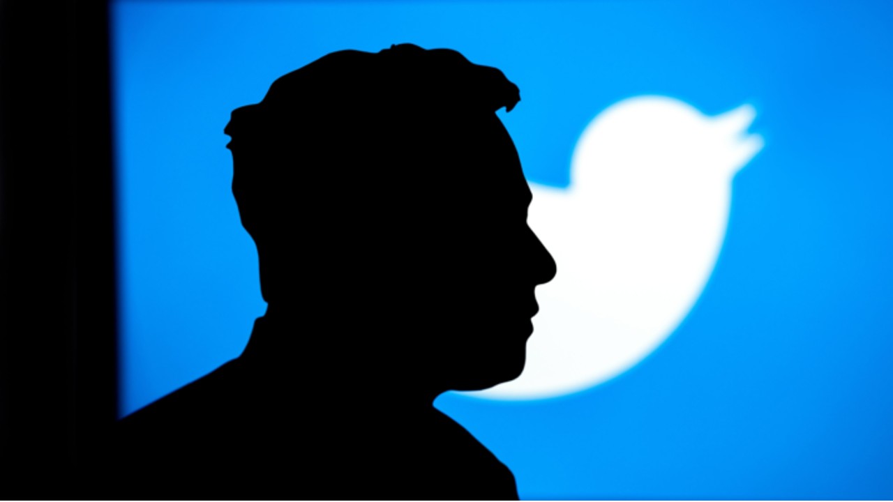 Image shows silhouette of Elon Musk's face with the Twitter logo in the background