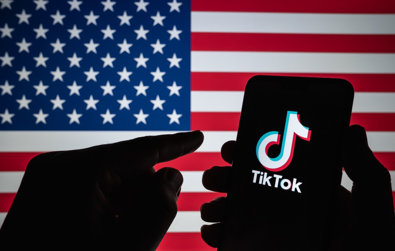 Image shows the TikTok logo with the US flag in the background
